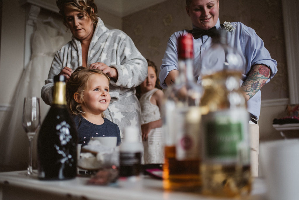Young flower girl staring happily into the distance as the bride fixes her hair
