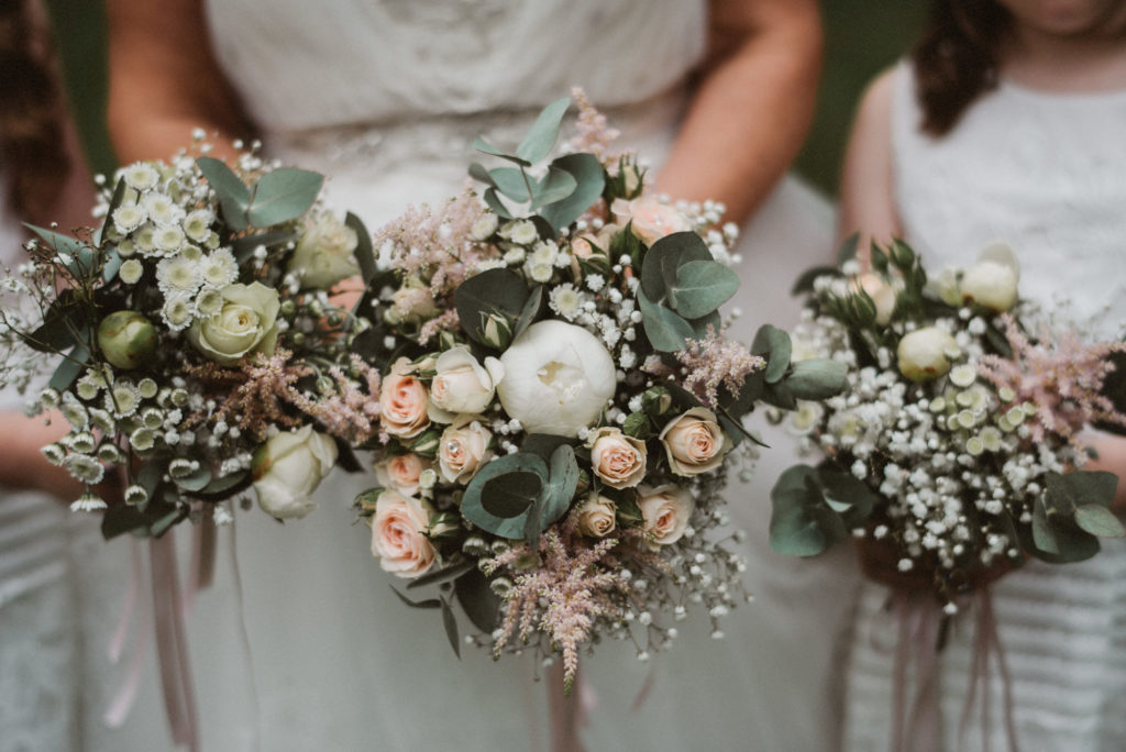 Three beautiful wedding bouquets held closely together by the bride and her two bridesmaids