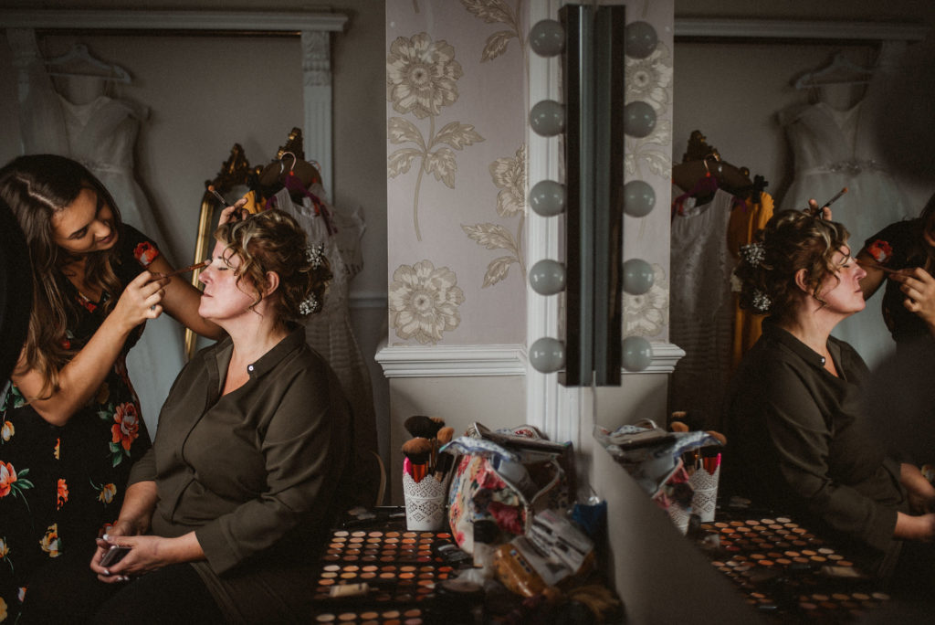 Bride getting her makeup done next to a mirror