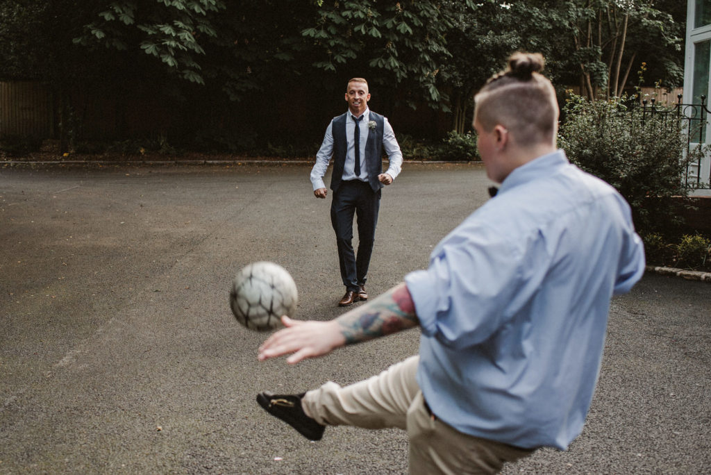 A wedding guest kicks a football towards another wedding guest