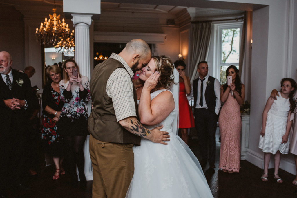 The bride wipes a tear from her eye during the first dance with her groom at Ashfield House