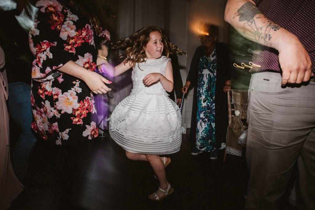 A girl in a white dress spins on the dance floor at a wedding