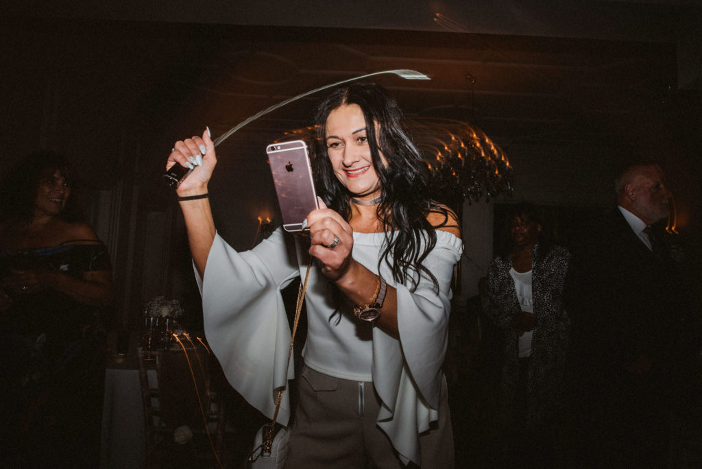 A woman holds her phone on the dance floor at a wedding