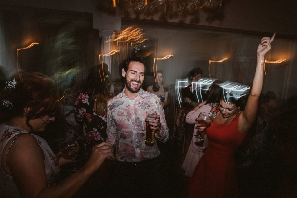 Two wedding guests dance enthusiastically during a wedding reception