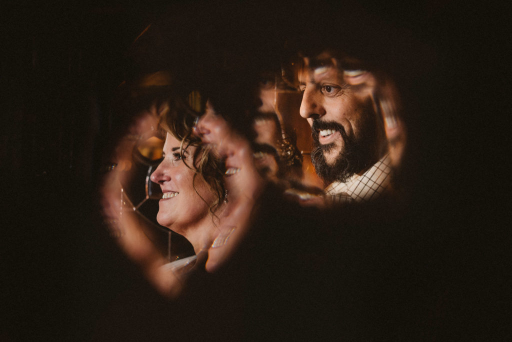 Bride and groom look towards a Nikon speedlight shot through stained glass