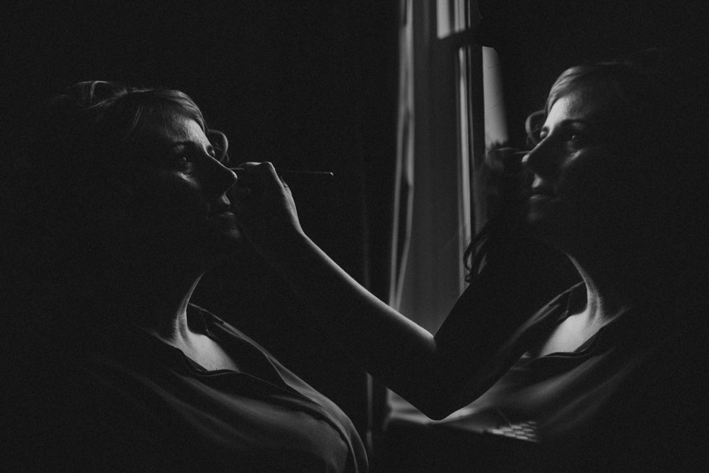 Black and white image of woman having her makeup applied