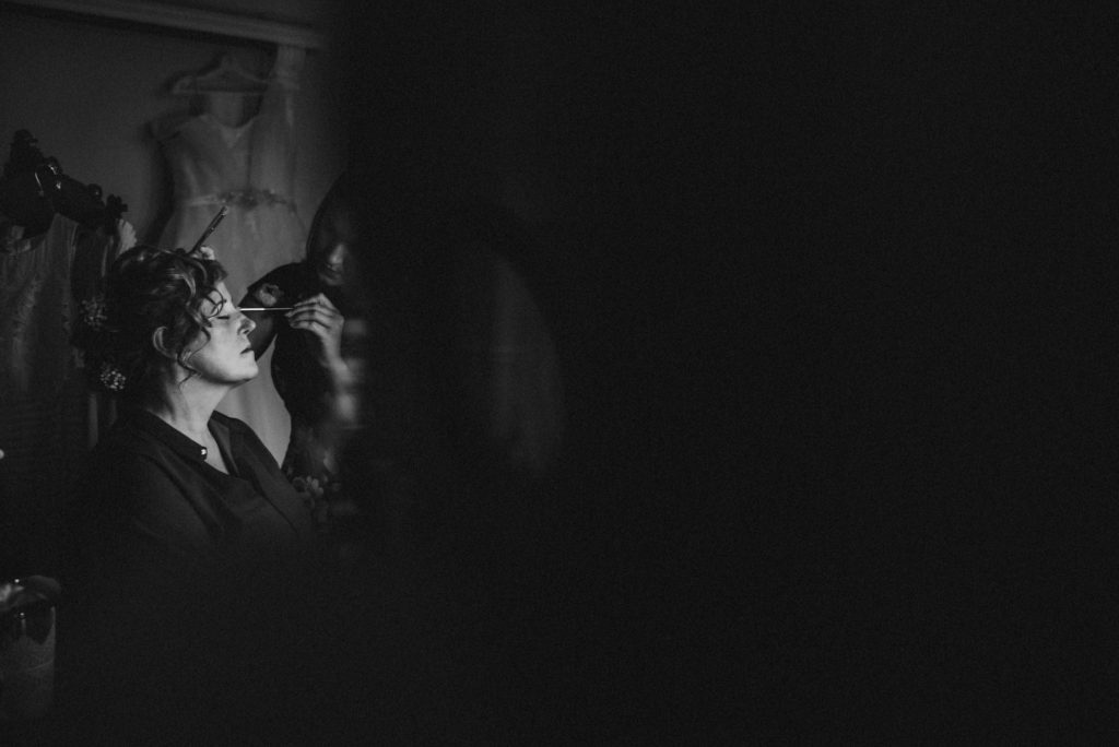 Black and white image of woman having eye shadow applied