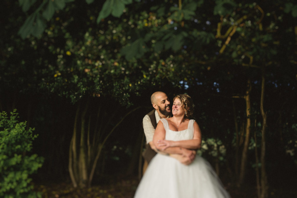 The groom wraps his arms around the bride romantically and they laugh together