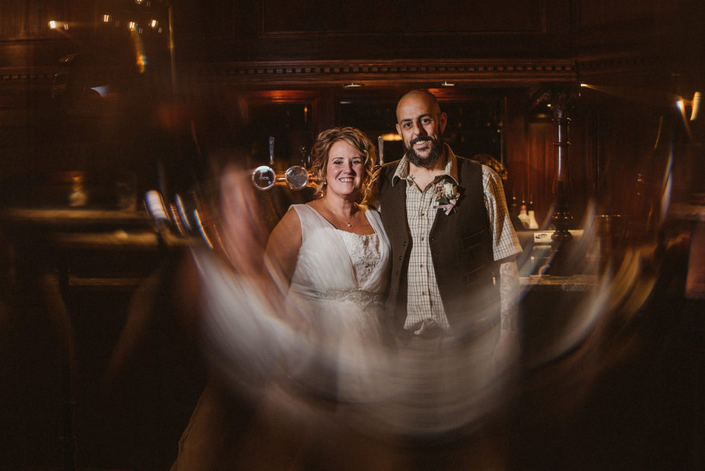 Bride and groom look directly at camera reflected through a stained glass door