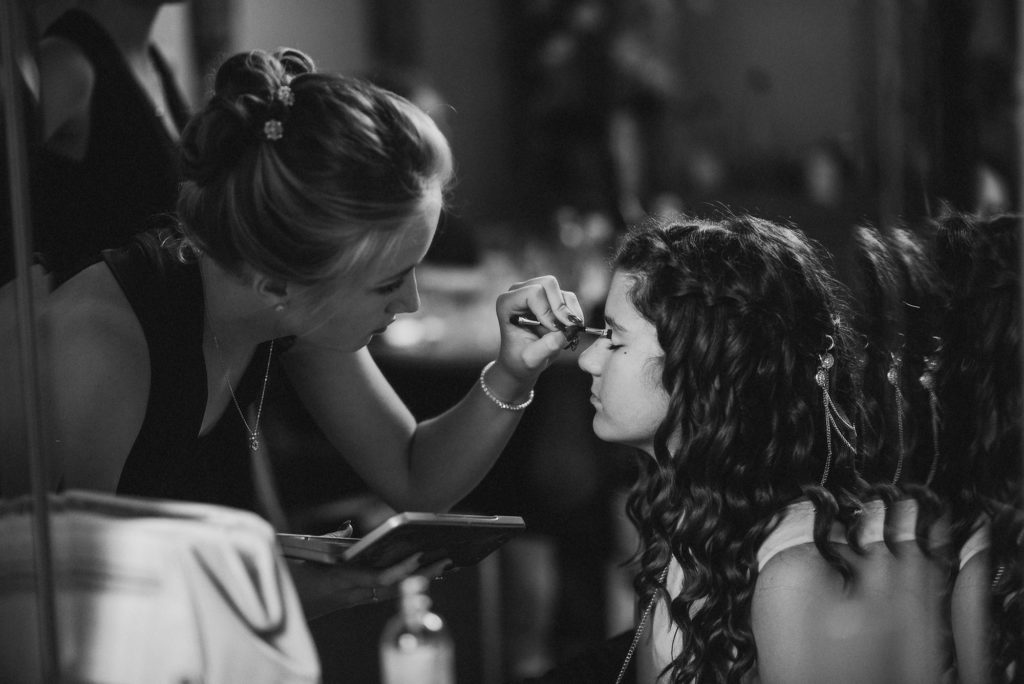 bridesmaid puts makeup on her friend