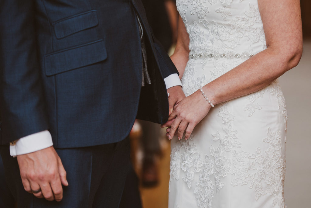 bride and groom hold hands during their wedding ceremony