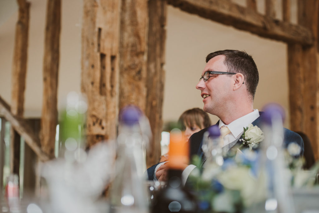 groom laughs during wedding breakfast speeches in the Celebration Barn