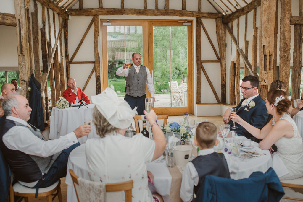 best man toasts the groom during the speeches at a relaxed barn wedding