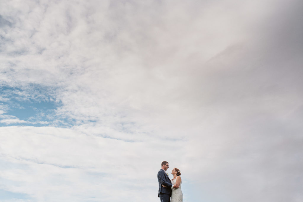Surrey bride and groom look at each other against a big blue sky