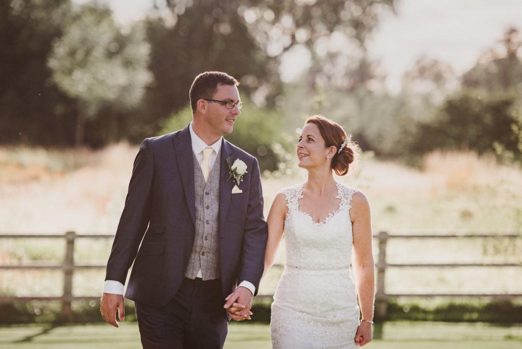 bride and groom walk along naturally in the golden light at their farm wedding