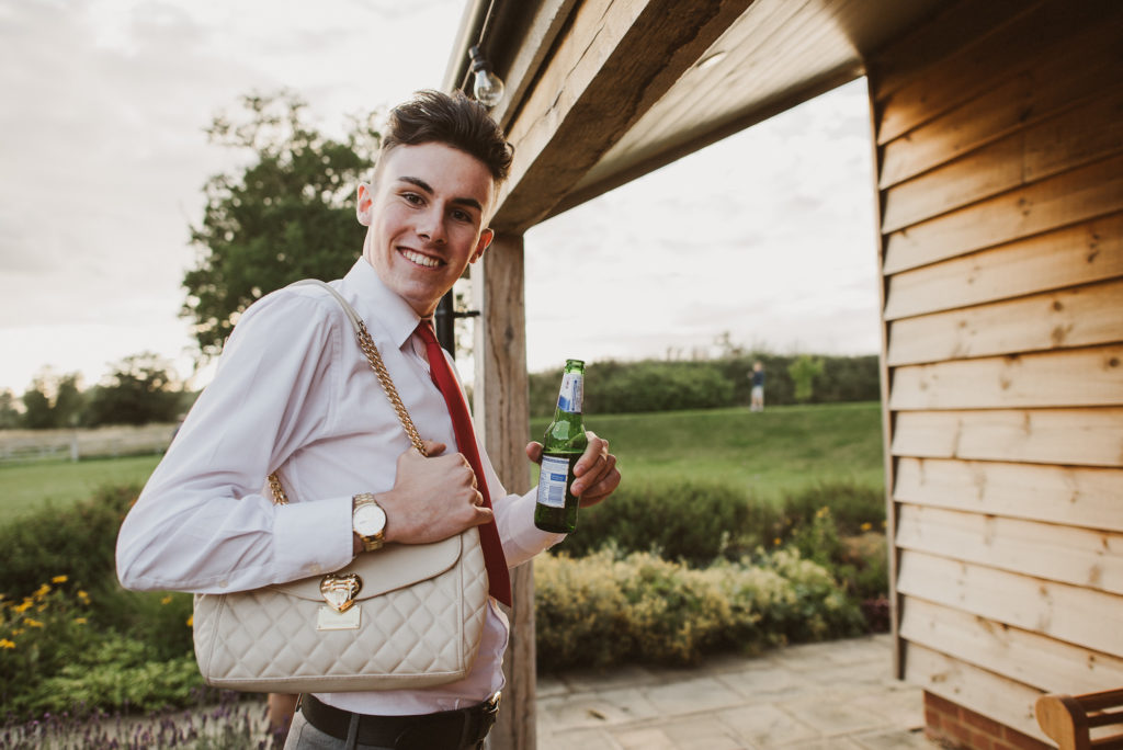 wedding guest holds handbag and laughs