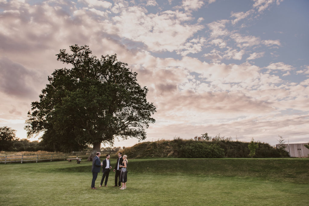wedding guests standing under a giant tree on the grass at Easton Grange