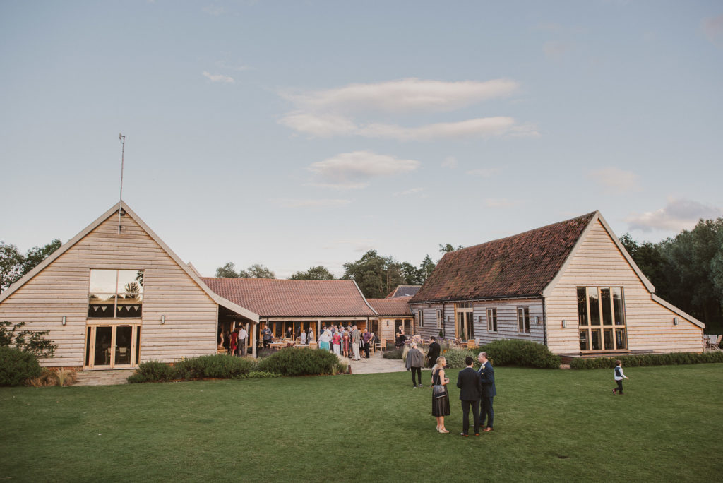 wedding guests stand outside the barn at Easton Grange