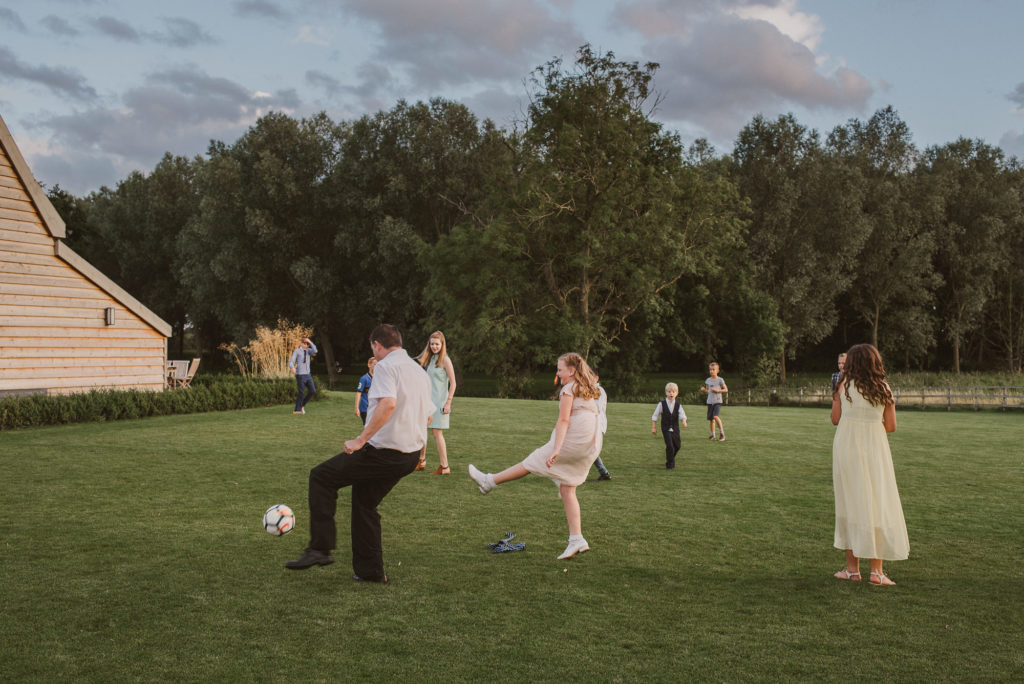 children play football at a wedding