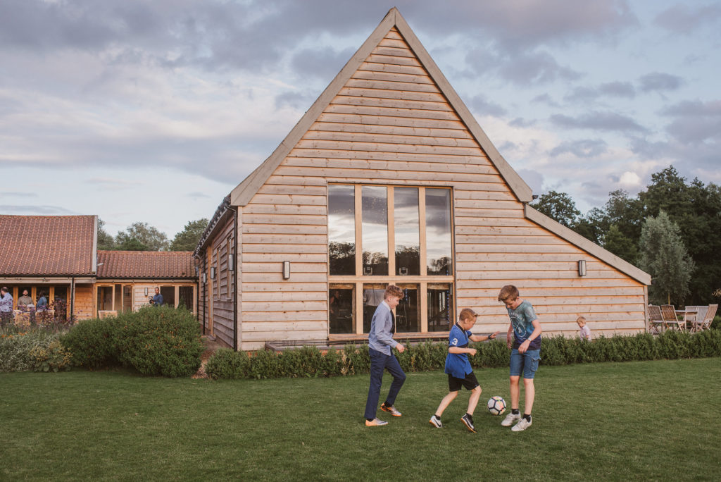 children play football outside of the Celebration Barn at Easton Grange