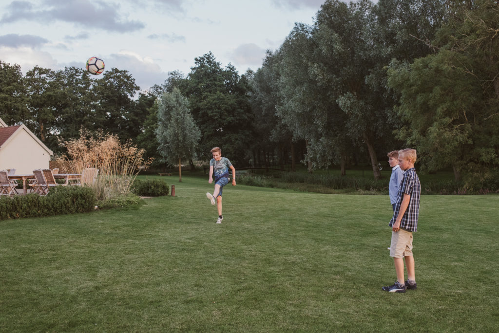 wedding guest kicks a football over the trees at a farm wedding