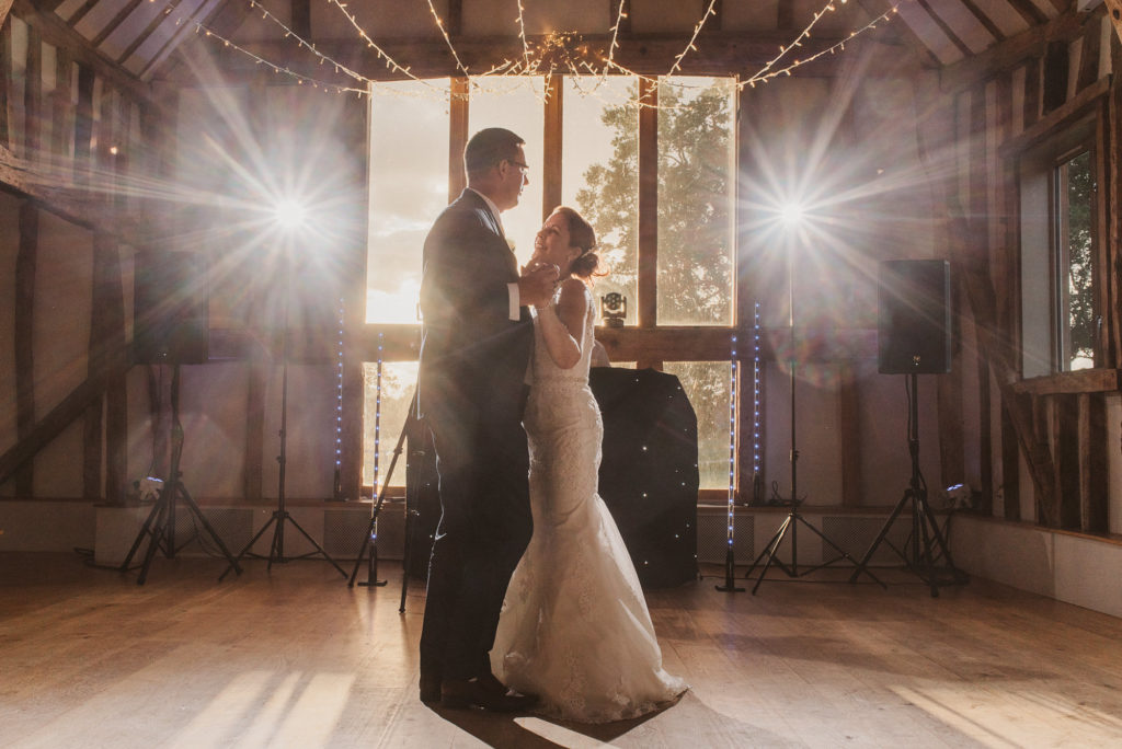 bride and groom look at each other during their first dance in a barn