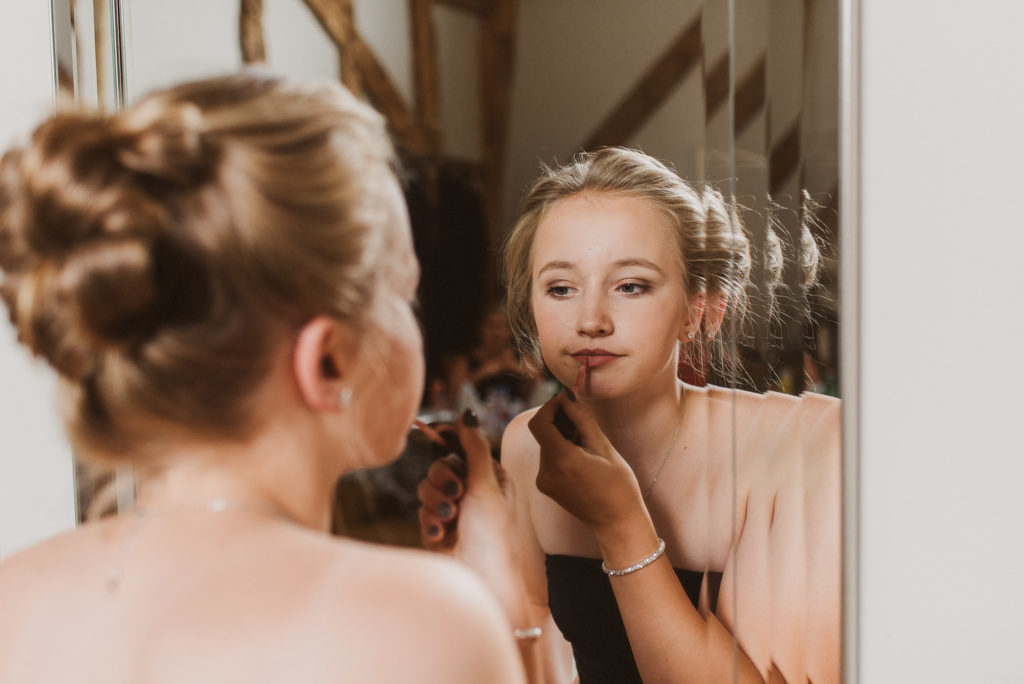 bridesmaid looks into the mirror and puts on lipstick