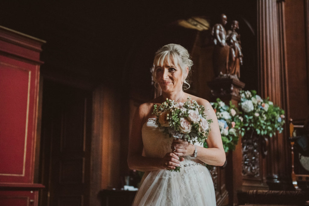 Berkshire bride looks happy as she walks up the aisle towards her groom in the Great Hall