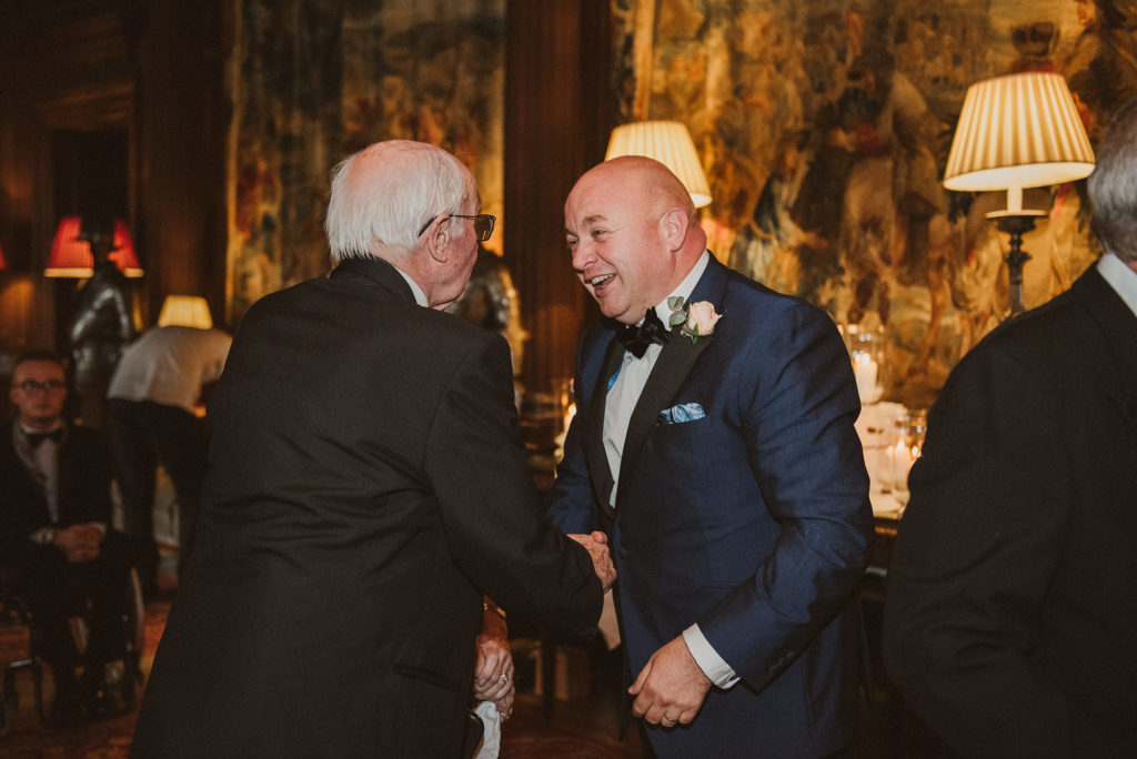 groom is congratulated by a wedding guest after his wedding ceremony