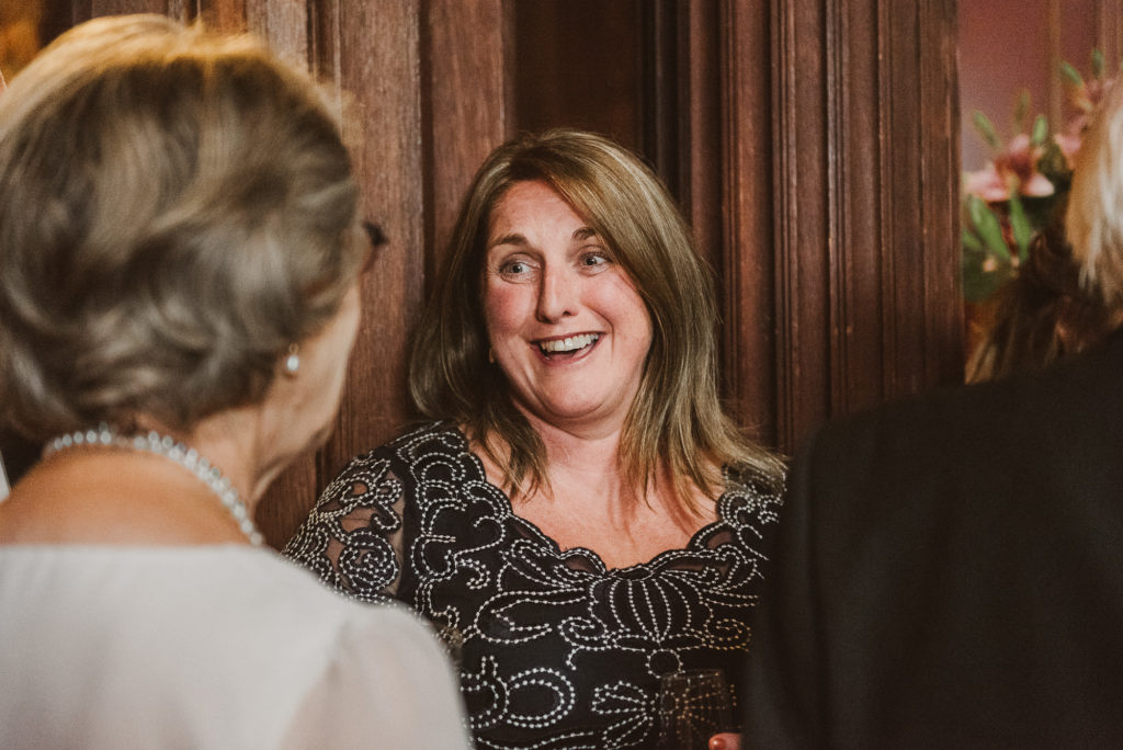 wedding guests laugh and enjoy themselves in the Great Hall at Cliveden House