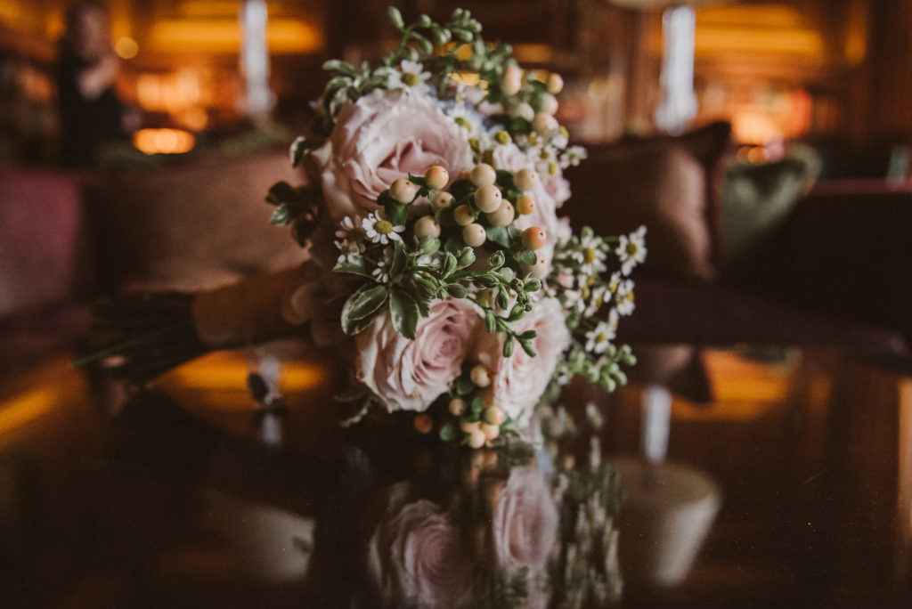 bridal bouquet with pink roses sits on reflective table