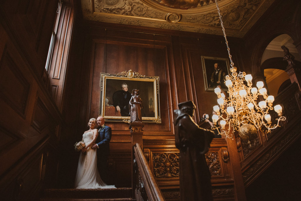 bride and groom next to the window on the main staircase at Cliveden House