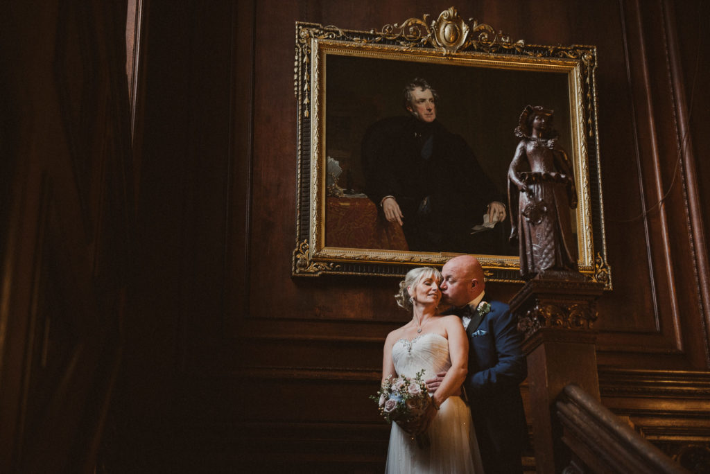 bride and groom cuddle on the grand staircase at Cliveden House