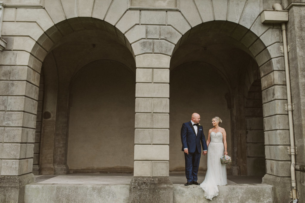 bride and groom stand under grand arches at Cliveden