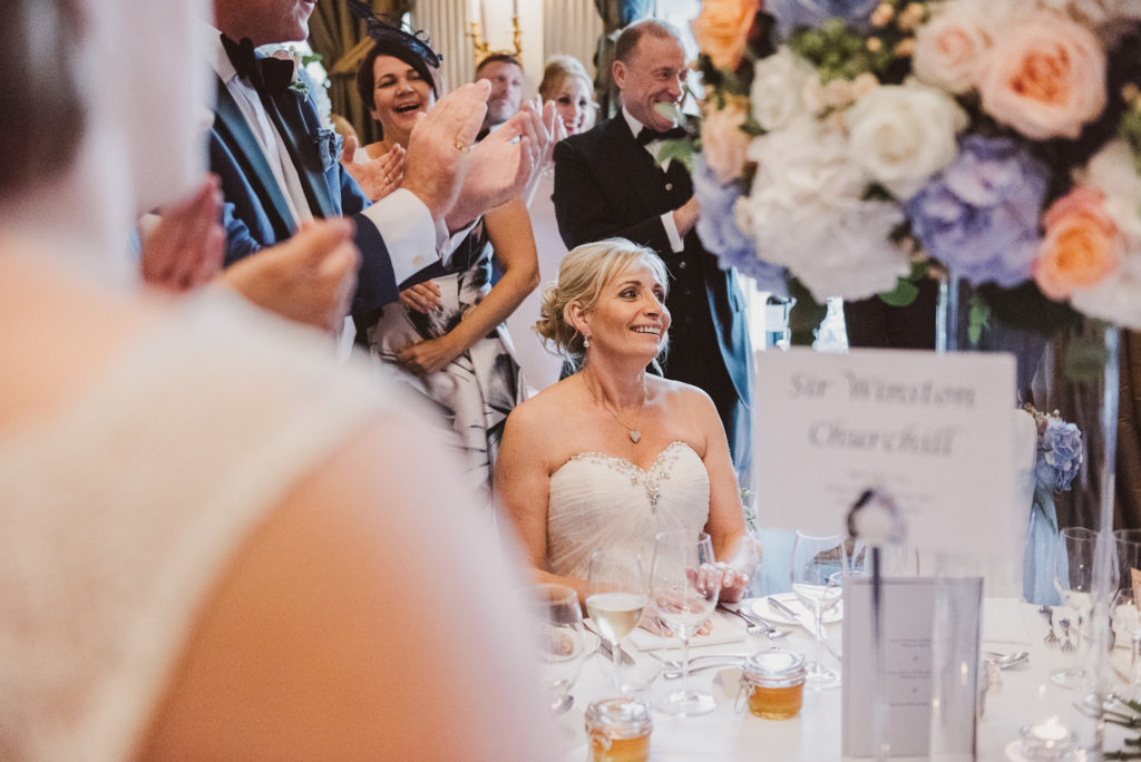 bride looks lovingly at her groom as he enters the room during their wedding breakfast