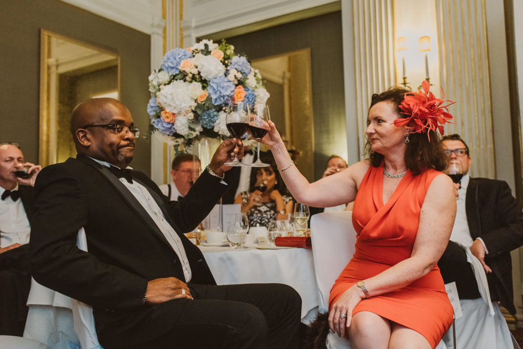 two wedding guests clink their glasses together during a wedding breakfast