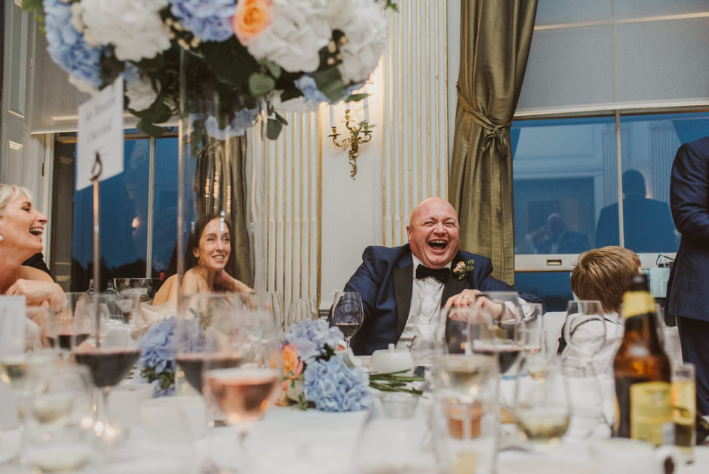 a groomsman looks very happy as his friend delivers a speech