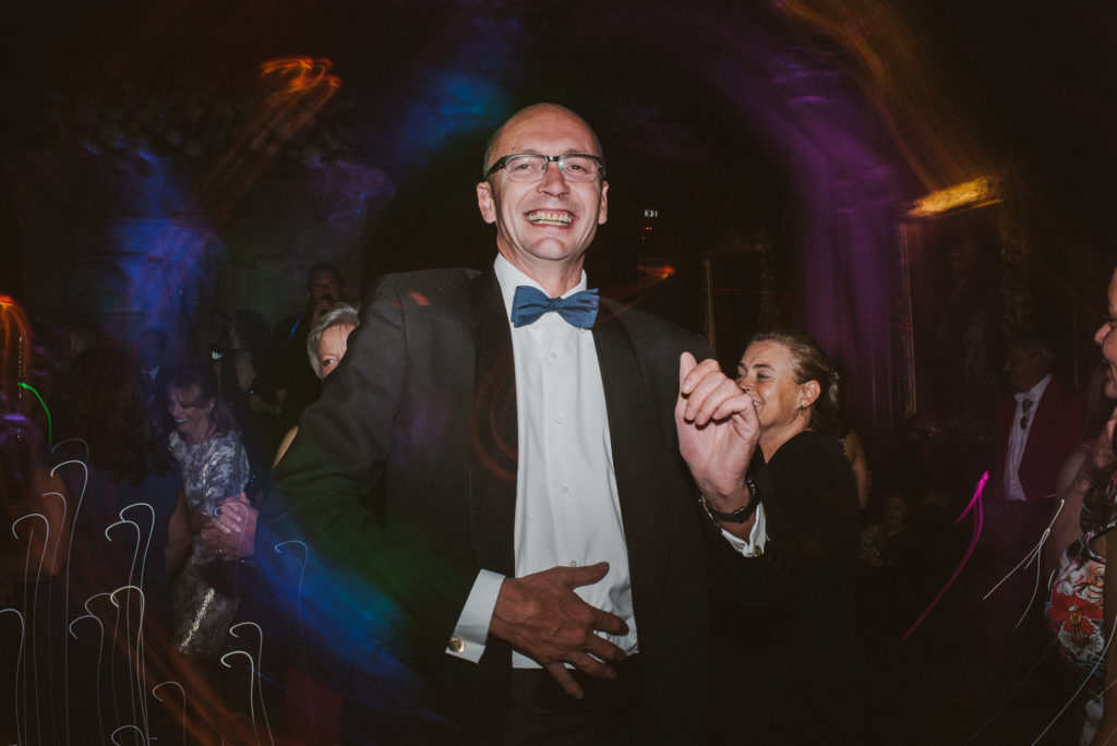 a wedding guest in a bow tie dances to the music