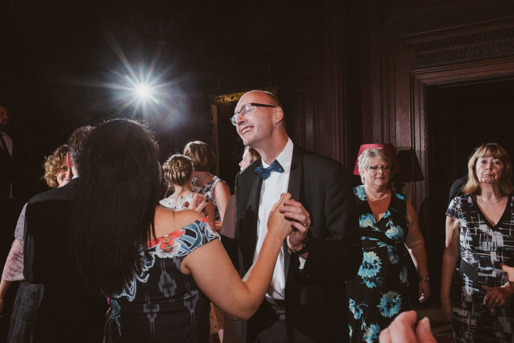 a man with glasses dances with a woman during a wedding reception