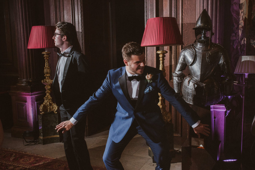 groomsman dances next to suits of armour