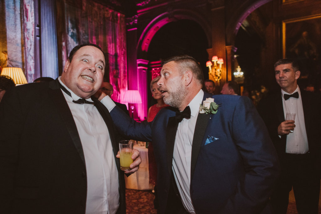 a wedding guest pulls the ear of a man in a bow tie in the Great Hall during a wedding reception