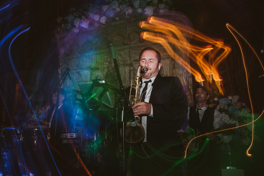 a man plays saxophone surrounded by light trails in the Great Hall at Cliveden