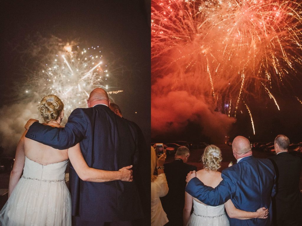 bride and groom watch fireworks outside Cliveden House in the rain