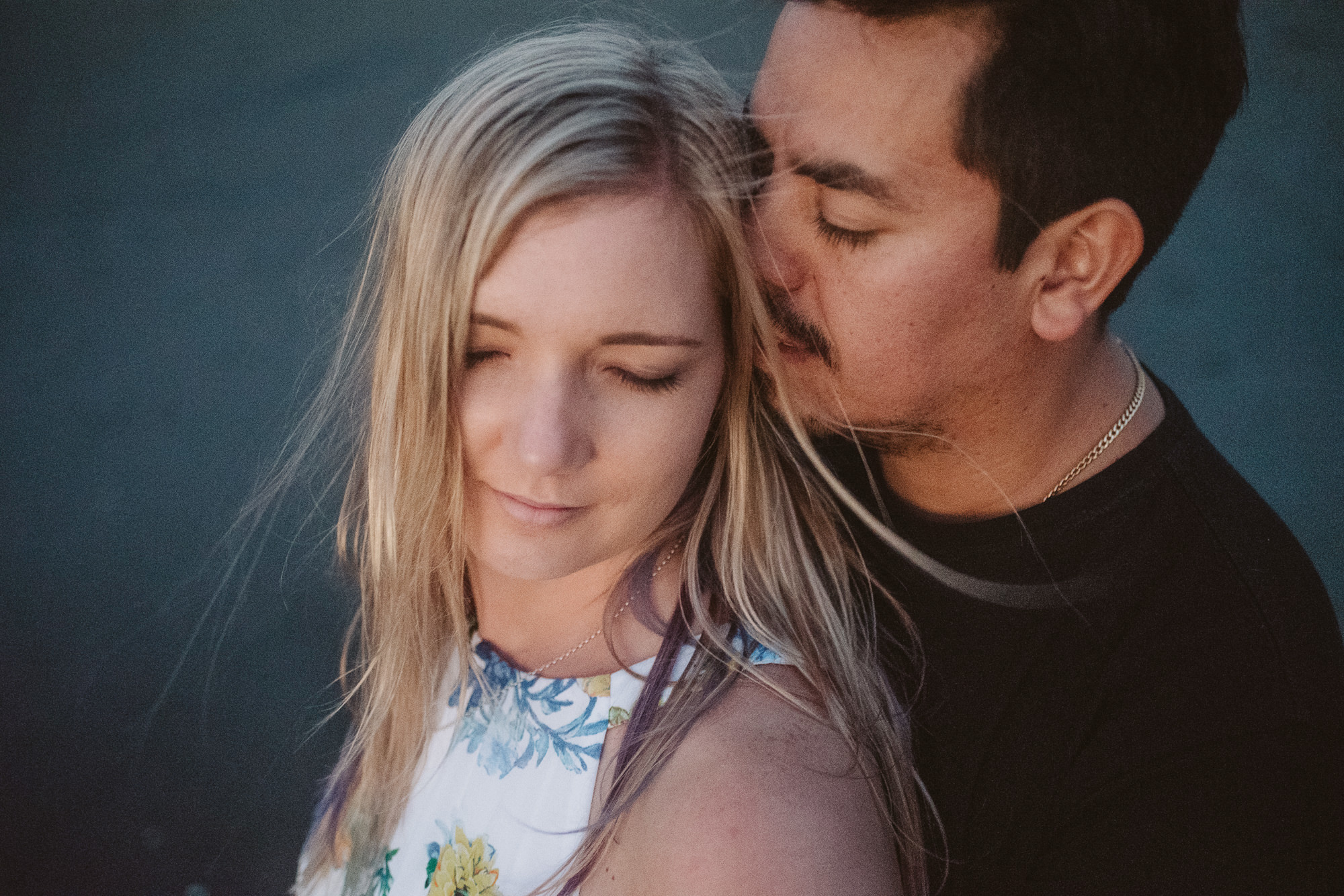 An engaged couple have an intimate moment on Piha Beach, New Zealand
