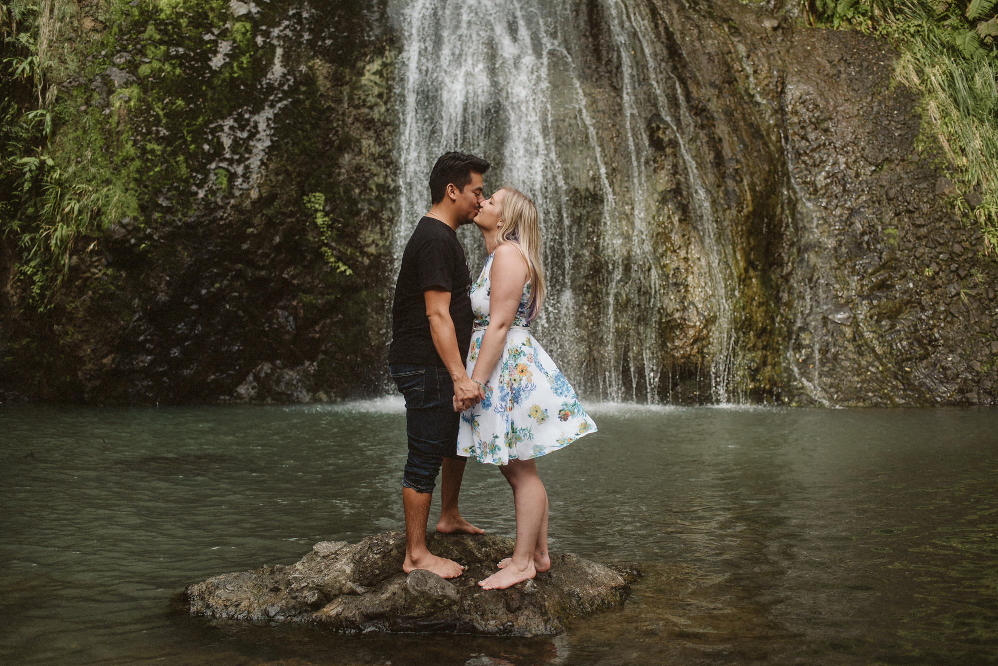 A couple have a kiss on a rock at Kitekite Falls in West Auckland