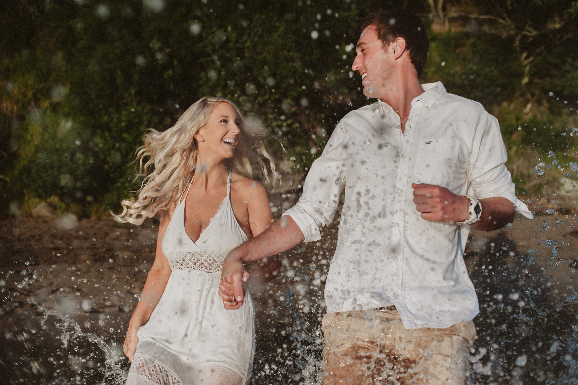 A couple runs into the ocean on the North Shore of Auckland, New Zealand