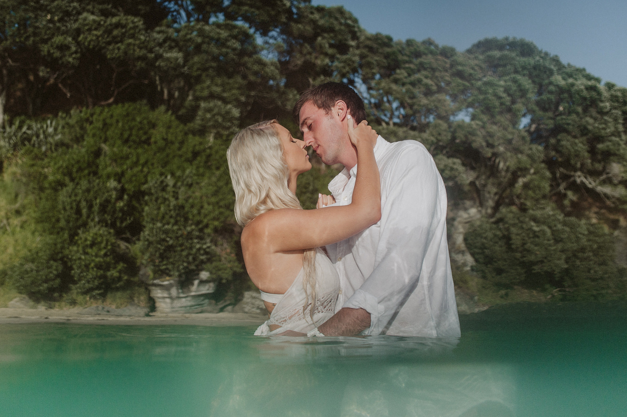 A couple embrace in the sea on the North Shore of Auckland