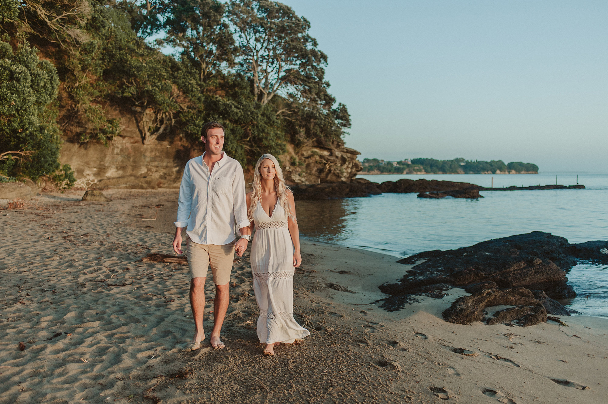 A couple walk along a North Shore beach in Auckland