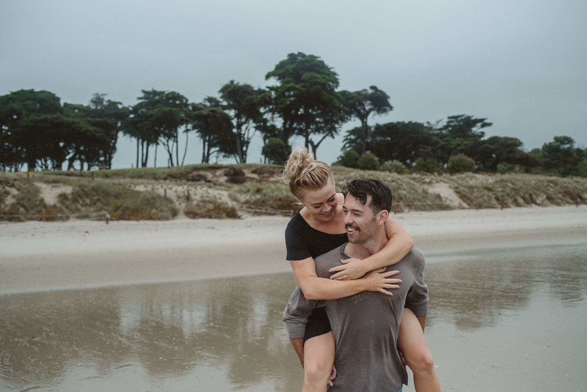 A man carrying a woman on his back in the Tawharanui Regional Park