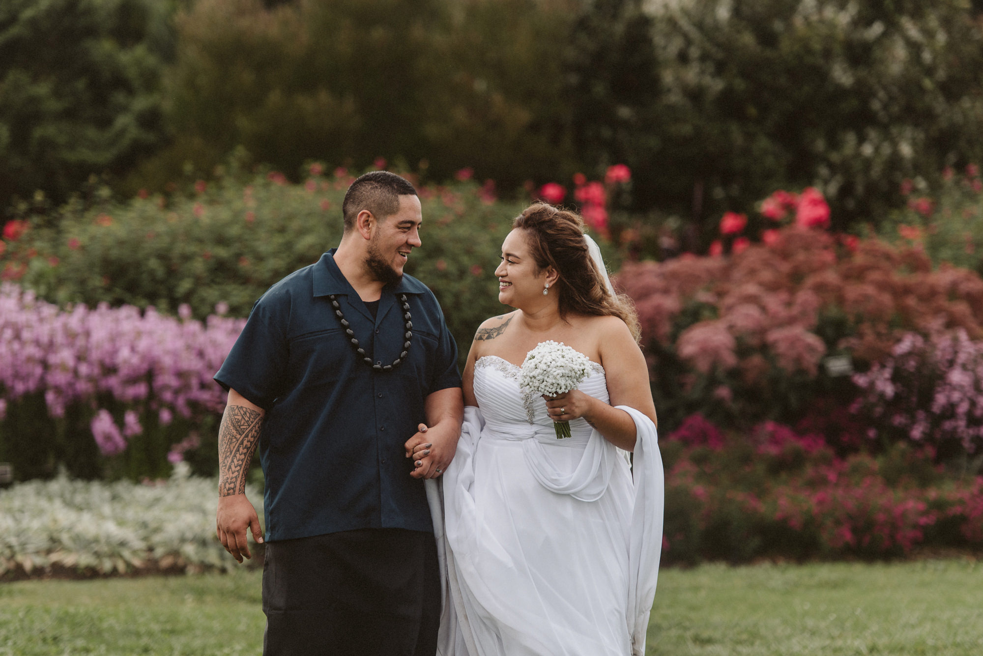 A couple walk along holding hands and looking into each others' eyes at Auckland Botanic Gardens